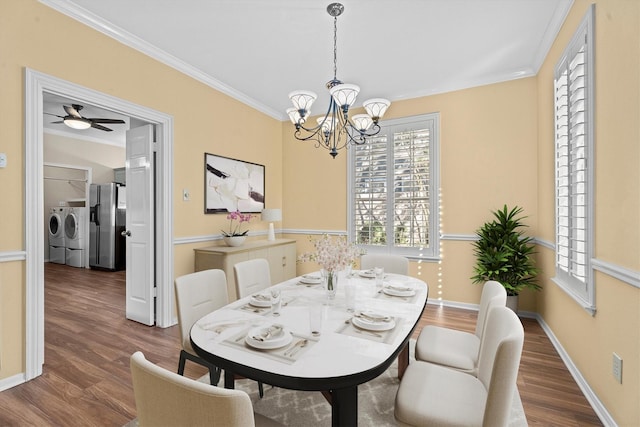 dining space with crown molding, washing machine and clothes dryer, dark hardwood / wood-style floors, and an inviting chandelier