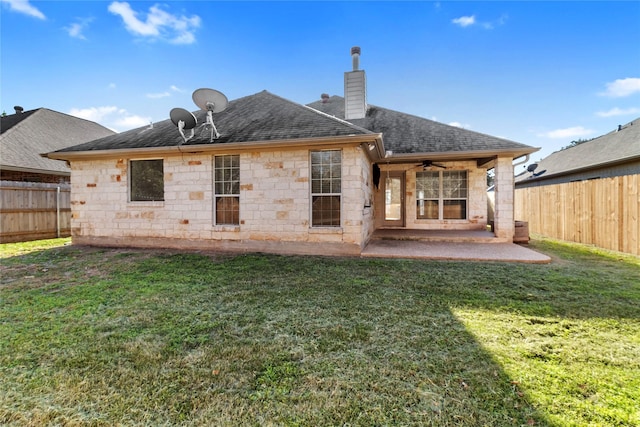 back of property with ceiling fan, a patio area, and a yard