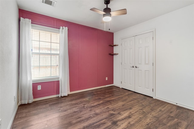 unfurnished bedroom with ceiling fan, a closet, and dark wood-type flooring