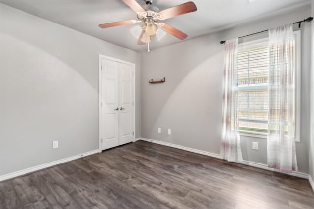 empty room with ceiling fan, a wealth of natural light, and dark hardwood / wood-style flooring