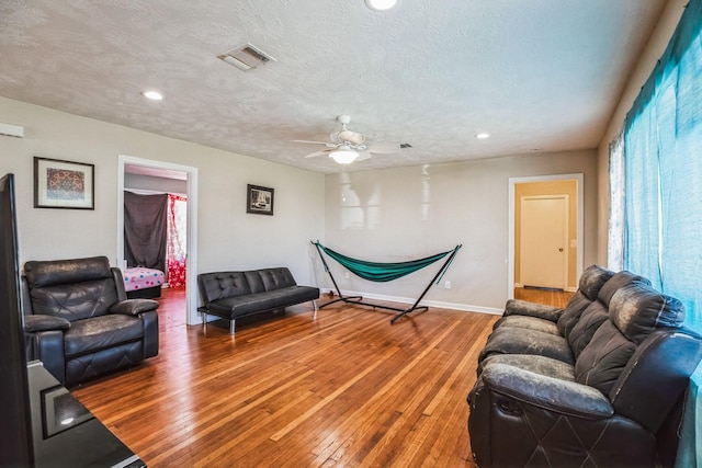 living room with ceiling fan, a textured ceiling, and hardwood / wood-style floors