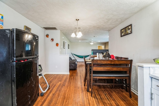 dining area with a textured ceiling, ceiling fan with notable chandelier, and hardwood / wood-style flooring