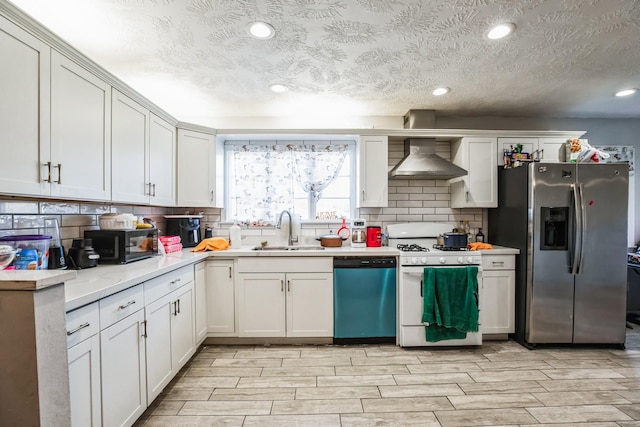 kitchen featuring white cabinets, wall chimney range hood, stainless steel appliances, tasteful backsplash, and sink