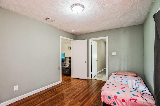 bedroom with a textured ceiling and dark hardwood / wood-style floors