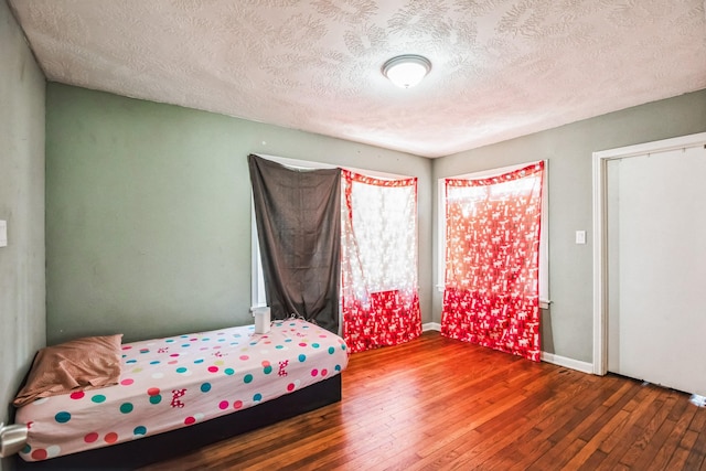 bedroom featuring dark hardwood / wood-style flooring and a textured ceiling