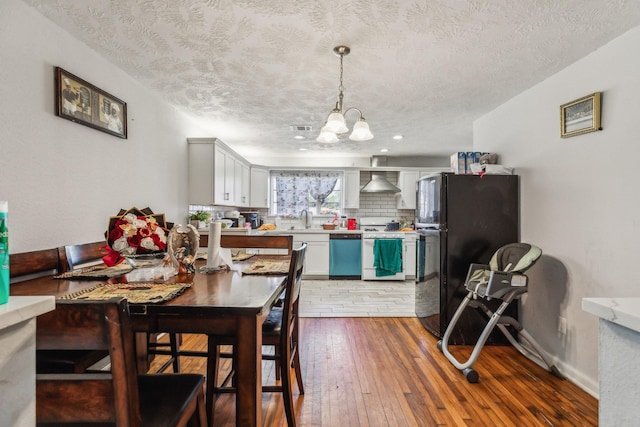 dining area with a textured ceiling, an inviting chandelier, dark hardwood / wood-style flooring, and sink