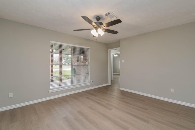 spare room with ceiling fan, a textured ceiling, and light wood-type flooring