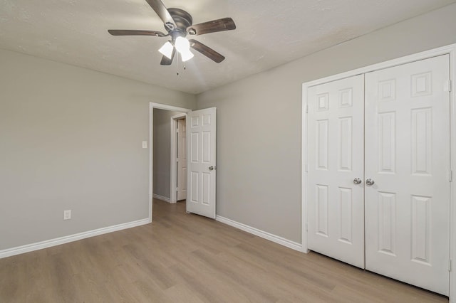 unfurnished bedroom featuring ceiling fan, a closet, and light hardwood / wood-style flooring