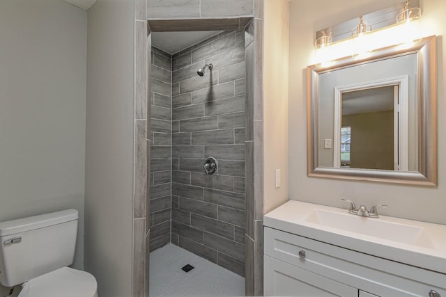 bathroom with toilet, tiled shower, and vanity