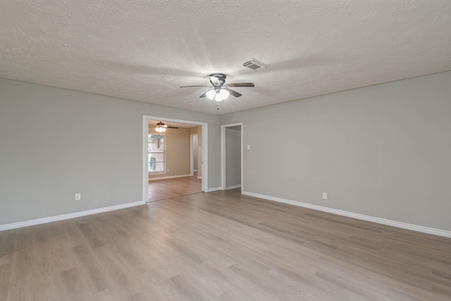 spare room featuring a textured ceiling and light hardwood / wood-style floors