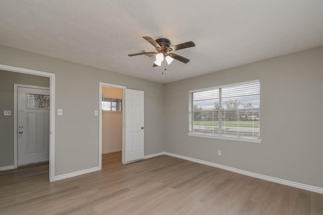 unfurnished bedroom featuring ceiling fan, a closet, a spacious closet, and light hardwood / wood-style floors