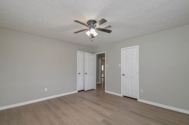 spare room featuring a textured ceiling, ceiling fan, and wood-type flooring