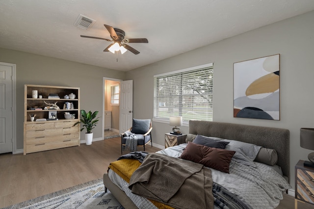 bedroom featuring ceiling fan, dark hardwood / wood-style flooring, and connected bathroom