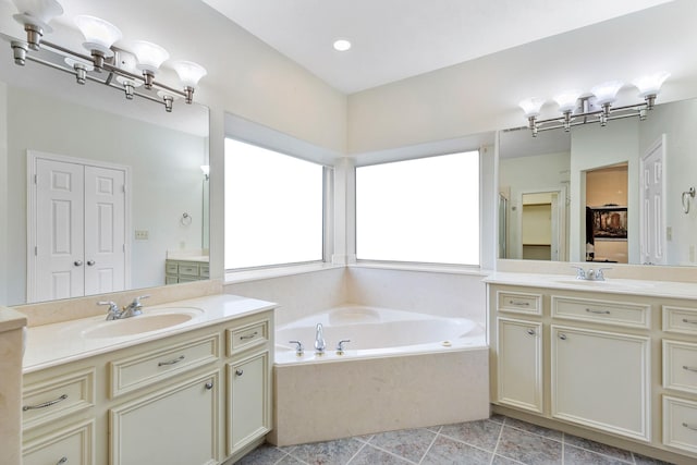 bathroom with tiled bath, vanity, and tile patterned flooring