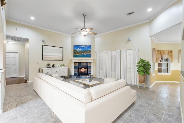 living room featuring ceiling fan, a tile fireplace, and crown molding