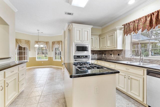 kitchen featuring stainless steel appliances, tasteful backsplash, a kitchen island, cream cabinets, and sink