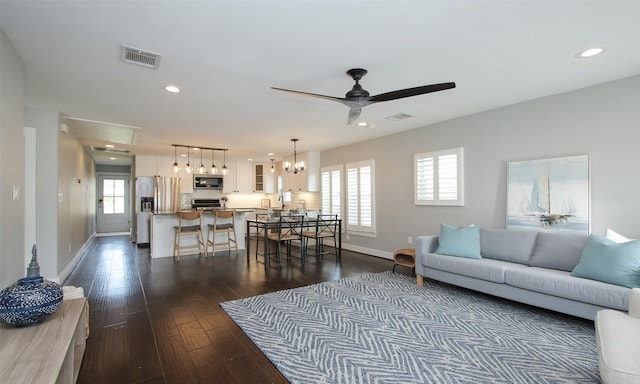 living room with ceiling fan with notable chandelier, dark hardwood / wood-style floors, and a healthy amount of sunlight