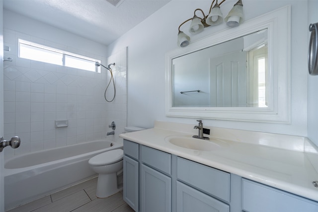 full bathroom featuring toilet, tiled shower / bath combo, tile patterned flooring, a textured ceiling, and vanity