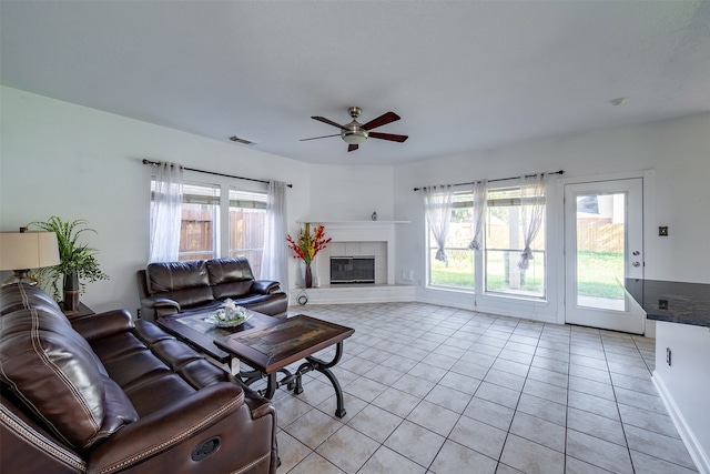 tiled living room featuring ceiling fan and a tiled fireplace