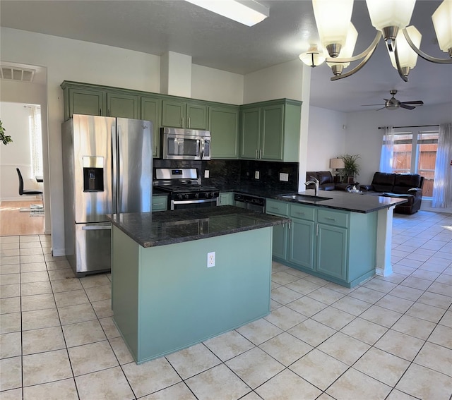 kitchen with kitchen peninsula, sink, appliances with stainless steel finishes, light tile patterned floors, and ceiling fan with notable chandelier