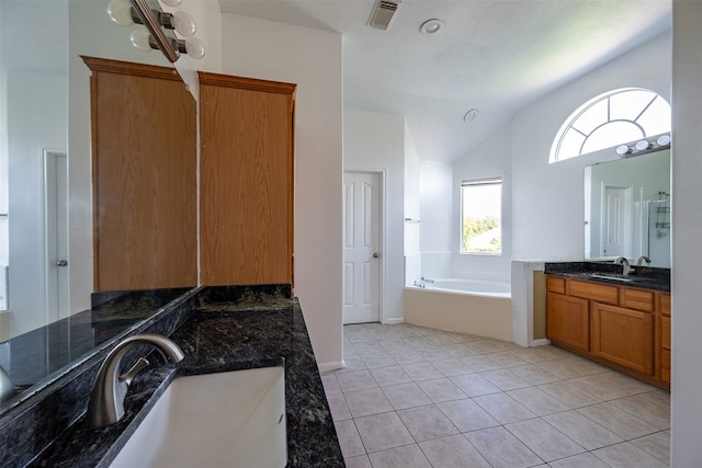 bathroom with vanity, tile patterned flooring, vaulted ceiling, and a bathing tub