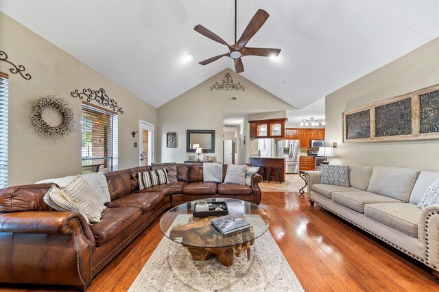 living room with ceiling fan, lofted ceiling, and light hardwood / wood-style flooring