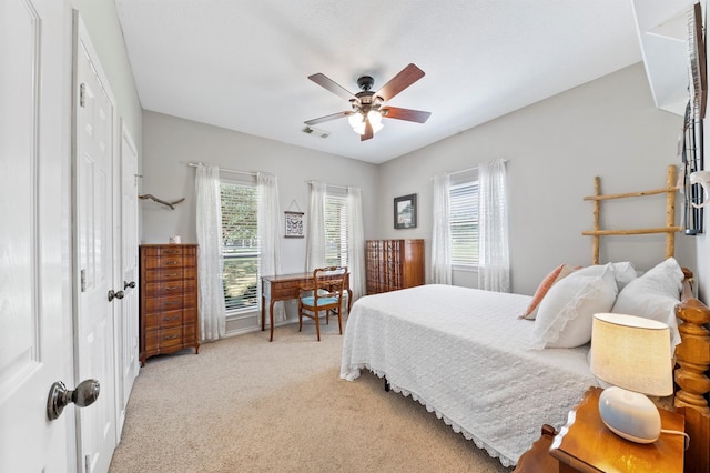 bedroom with multiple windows, ceiling fan, a closet, and light carpet