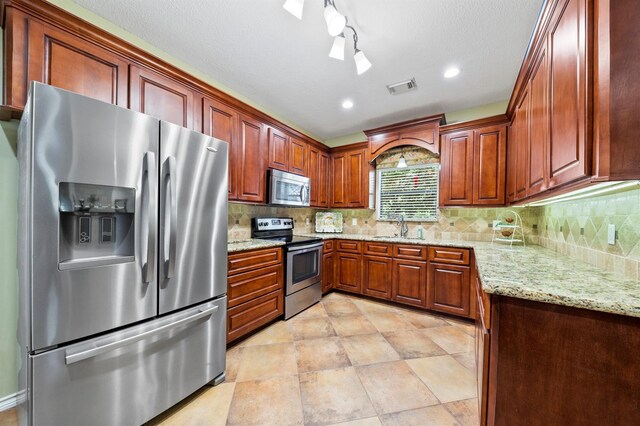 kitchen with light stone counters, sink, stainless steel appliances, and track lighting