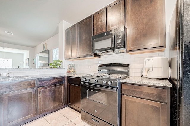 kitchen with tasteful backsplash, sink, light stone countertops, dark brown cabinets, and range with gas stovetop