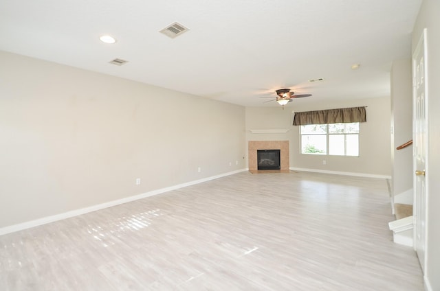 unfurnished living room with a fireplace, ceiling fan, and light wood-type flooring