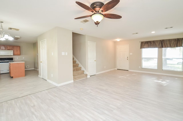 unfurnished living room featuring ceiling fan with notable chandelier and light hardwood / wood-style flooring