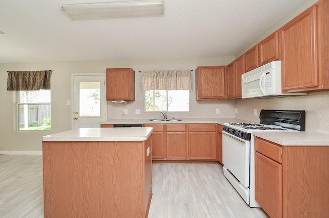 kitchen featuring sink, a center island, a healthy amount of sunlight, white appliances, and light hardwood / wood-style flooring