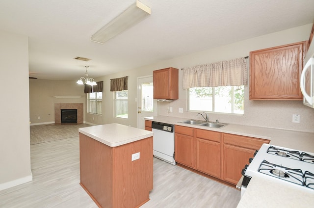 kitchen featuring sink, a tile fireplace, dishwasher, a center island, and a chandelier