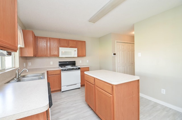 kitchen featuring white appliances, a center island, sink, and light hardwood / wood-style flooring