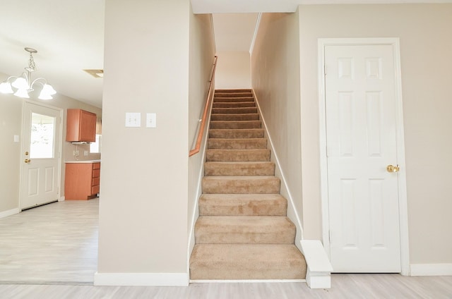 staircase with a notable chandelier and hardwood / wood-style flooring