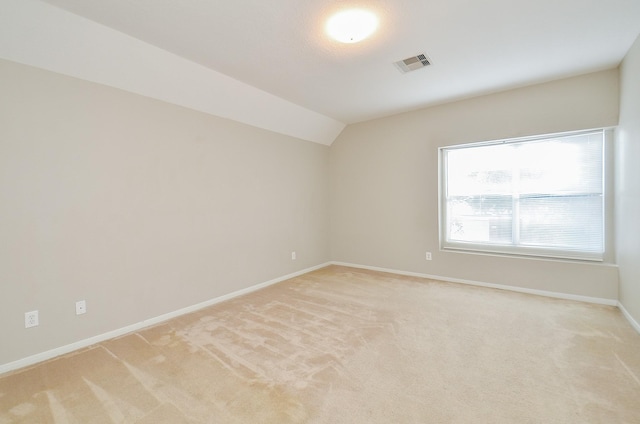 unfurnished room featuring lofted ceiling and light colored carpet