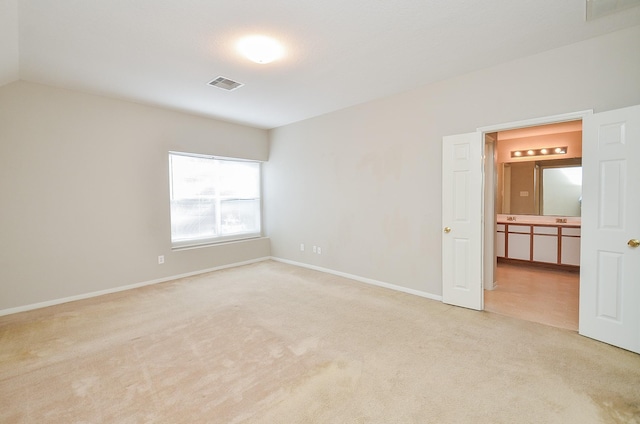 unfurnished room featuring lofted ceiling and light colored carpet