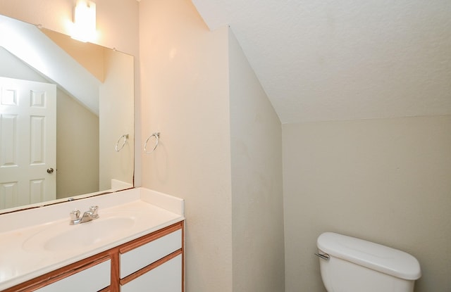 bathroom featuring vaulted ceiling, vanity, and toilet