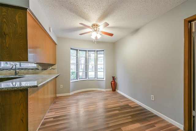 kitchen with ceiling fan, backsplash, hardwood / wood-style floors, sink, and a textured ceiling