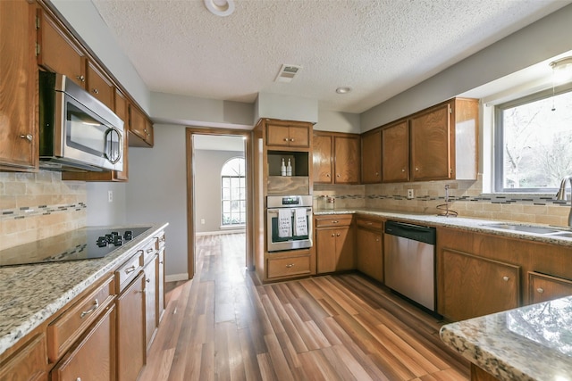 kitchen with tasteful backsplash, sink, hardwood / wood-style flooring, a textured ceiling, and stainless steel appliances