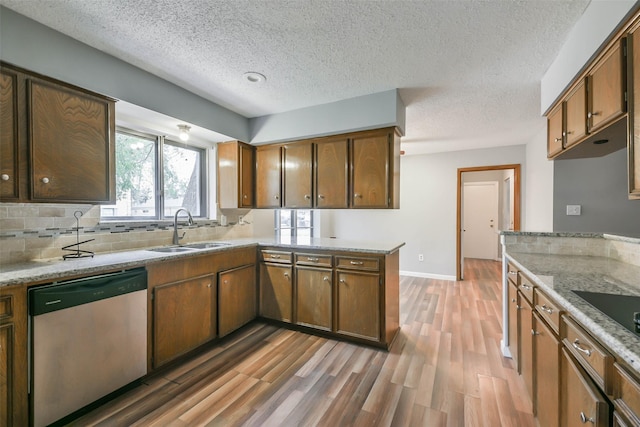 kitchen featuring sink, a textured ceiling, dishwasher, and kitchen peninsula