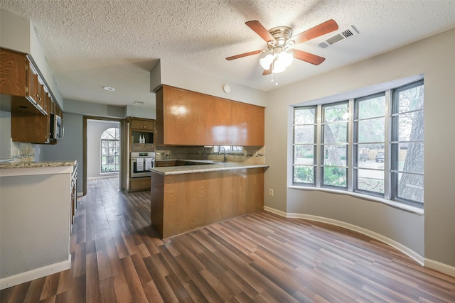 kitchen featuring kitchen peninsula, dark wood-type flooring, a wealth of natural light, and stainless steel appliances