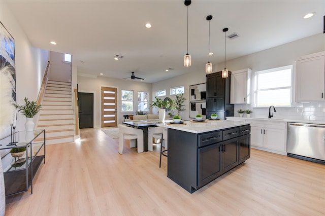 kitchen featuring dishwasher, a center island, decorative light fixtures, white cabinetry, and ceiling fan