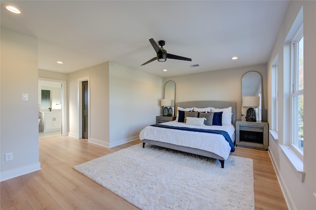 bedroom with ceiling fan, light wood-type flooring, ensuite bathroom, and multiple windows