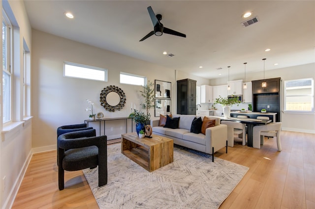 living room with light wood-type flooring and ceiling fan