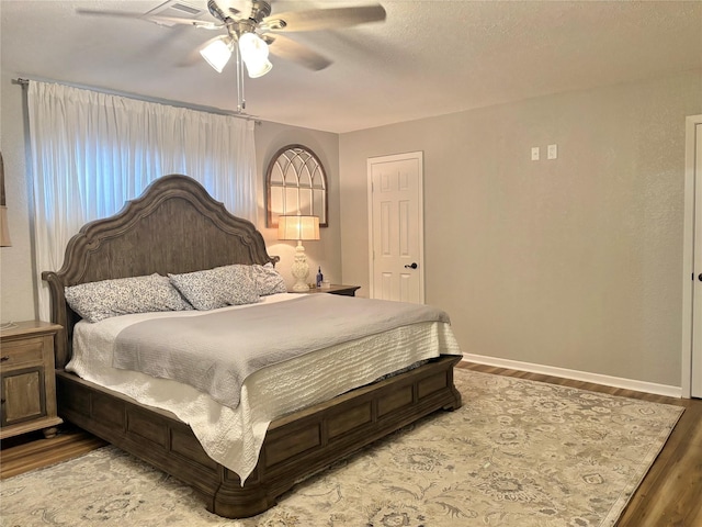 bedroom with hardwood / wood-style flooring, a textured ceiling, and ceiling fan