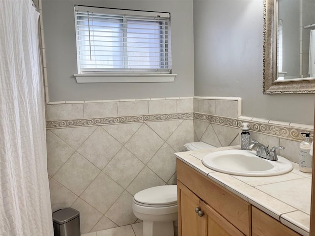 bathroom with tile walls, vanity, tile patterned floors, and toilet