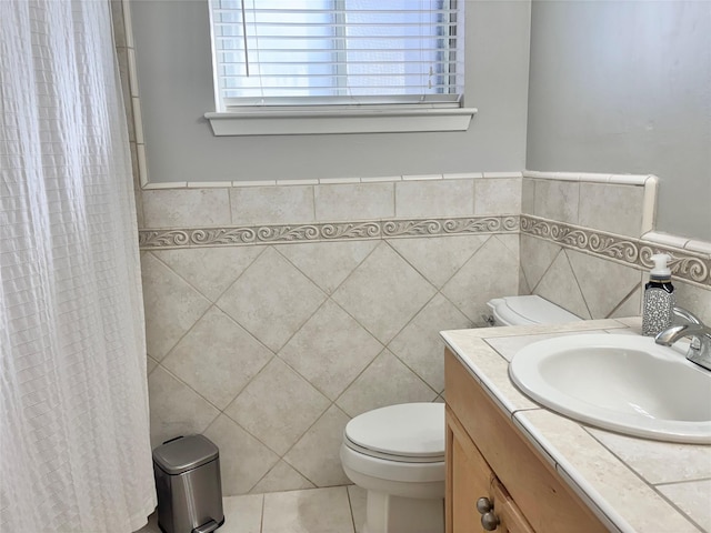 bathroom with tile patterned floors, toilet, tile walls, and vanity