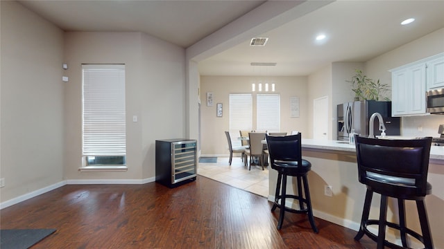 kitchen with wine cooler, dark wood-type flooring, a kitchen bar, appliances with stainless steel finishes, and white cabinets