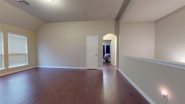 empty room with dark hardwood / wood-style flooring and vaulted ceiling